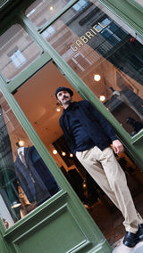 Titouan sur le pas de porte de la boutique Maison Gabriel Paris porte le cardigan Ayden en laine bleu marine LE MINOR X GABRIEL - Collection Automne Hiver 2025 - Maison Gabriel Paris