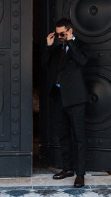 Élie prend la pose devant l'Hôtel Coste à Paris et porte le costume croisé Titouan en lin irlandais noir - Collection Printemps Été 2025 par Maison Gabriel Paris