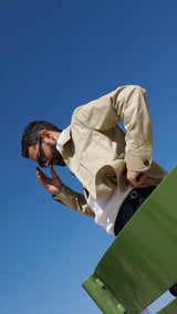 Élie aux Tuileries prend la pose et porte la veste de peintre Éliézer en coton vert sauge - Collection Printemps été 2025 - Maison Gabriel Paris