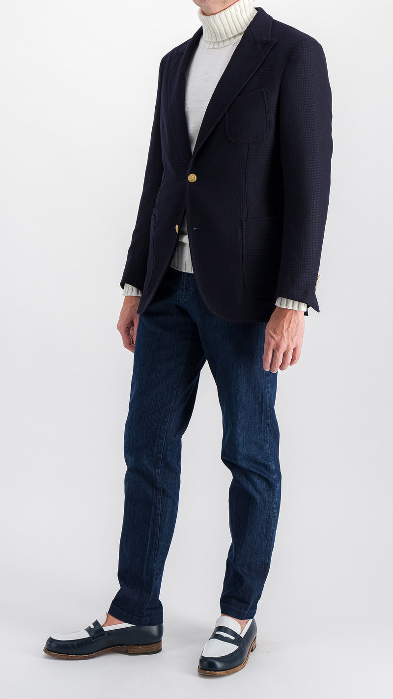 Le mannequin studio porte le blazer Ripley en laine natté bleu marine et le pull Philippe col roulé en laine mérinos blanc de la collection Plein Soleil et le jean Arthur, vue côté, de la Maison Gabriel Paris