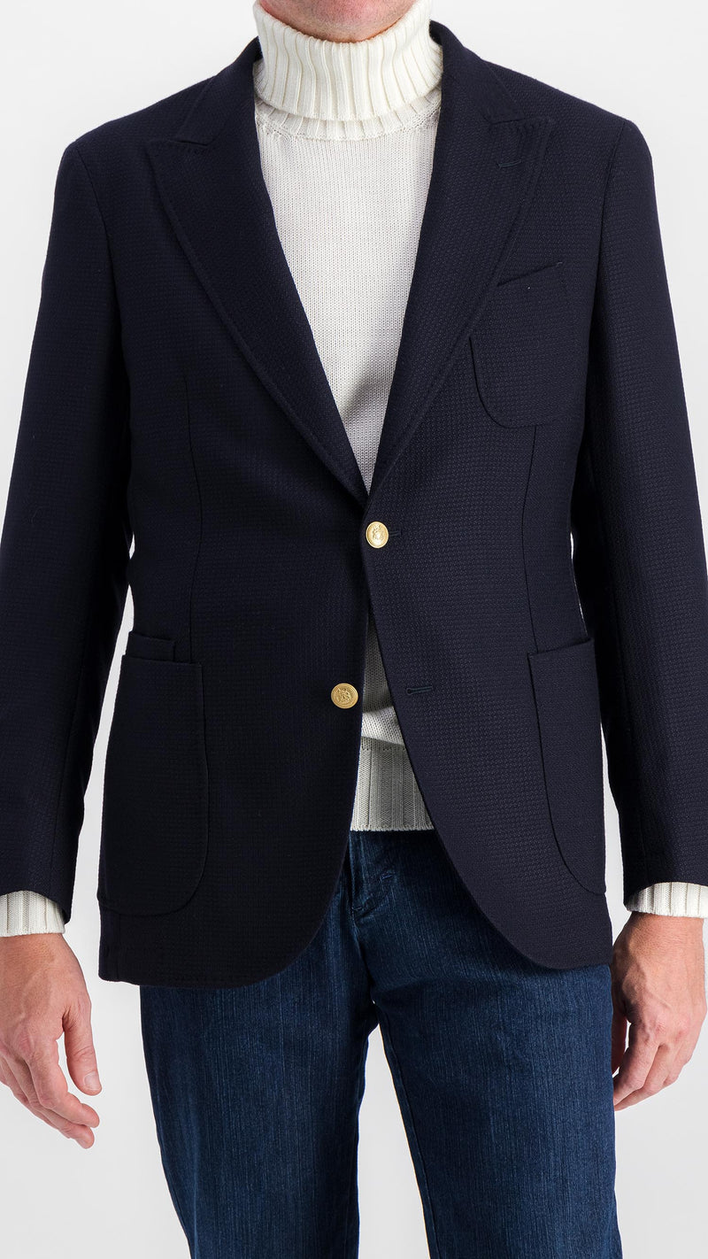 Le mannequin studio porte le blazer Ripley en laine natté bleu marine et le pull Philippe col roulé en laine mérinos blanc de la collection Plein Soleil et le jean Arthur, vue 3/4 face, de la Maison Gabriel Paris