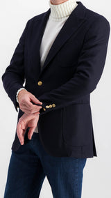 Le mannequin studio porte le blazer Ripley en laine natté bleu marine et le pull Philippe col roulé en laine mérinos blanc de la collection Plein Soleil et le jean Arthur, vue 3/4 côté, de la Maison Gabriel Paris