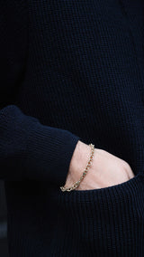 Titouan sur le pas de porte de la boutique Maison Gabriel Paris porte le cardigan Ayden en laine bleu marine LE MINOR X GABRIEL - zoom sur détail poche - Collection Automne Hiver 2025 - Maison Gabriel Paris