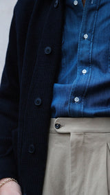 Titouan sur le pas de porte de la boutique Maison Gabriel Paris porte le cardigan Ayden en laine bleu marine LE MINOR X GABRIEL - zoom sur détail - Collection Automne Hiver 2025 - Maison Gabriel Paris