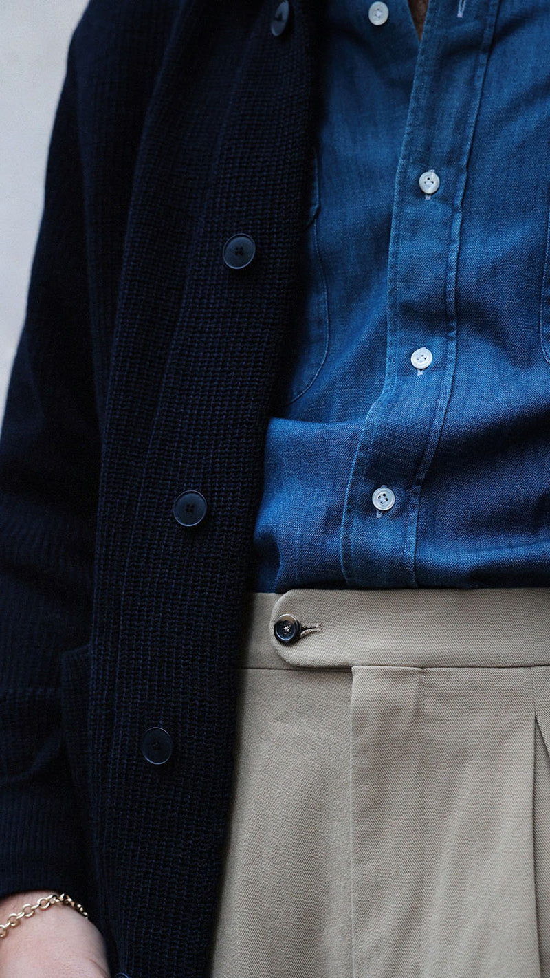 Titouan sur le pas de porte de la boutique Maison Gabriel Paris porte le cardigan Ayden en laine bleu marine LE MINOR X GABRIEL - zoom sur détail - Collection Automne Hiver 2025 - Maison Gabriel Paris