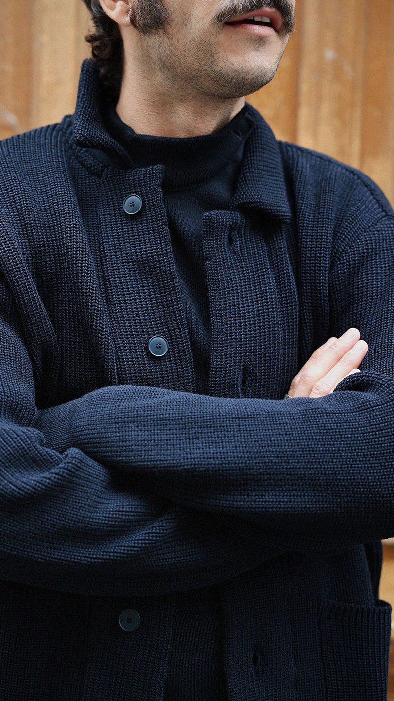 Titouan sur le pas de porte de la boutique Maison Gabriel Paris porte le cardigan Ayden en laine bleu marine LE MINOR X GABRIEL - zoom sur détail - Collection Automne Hiver 2025 - Maison Gabriel Paris