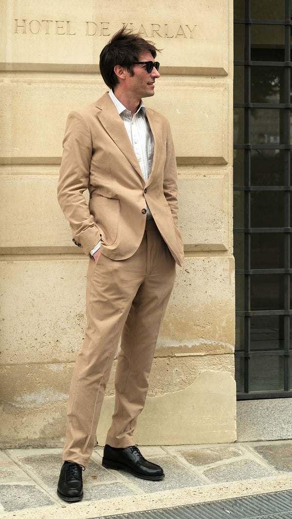 Devant l'Hôtel de Harley, Guillaume porte le costume Charly en milleraies d'été beige de la Maison Gabriel Paris - UNISEXE