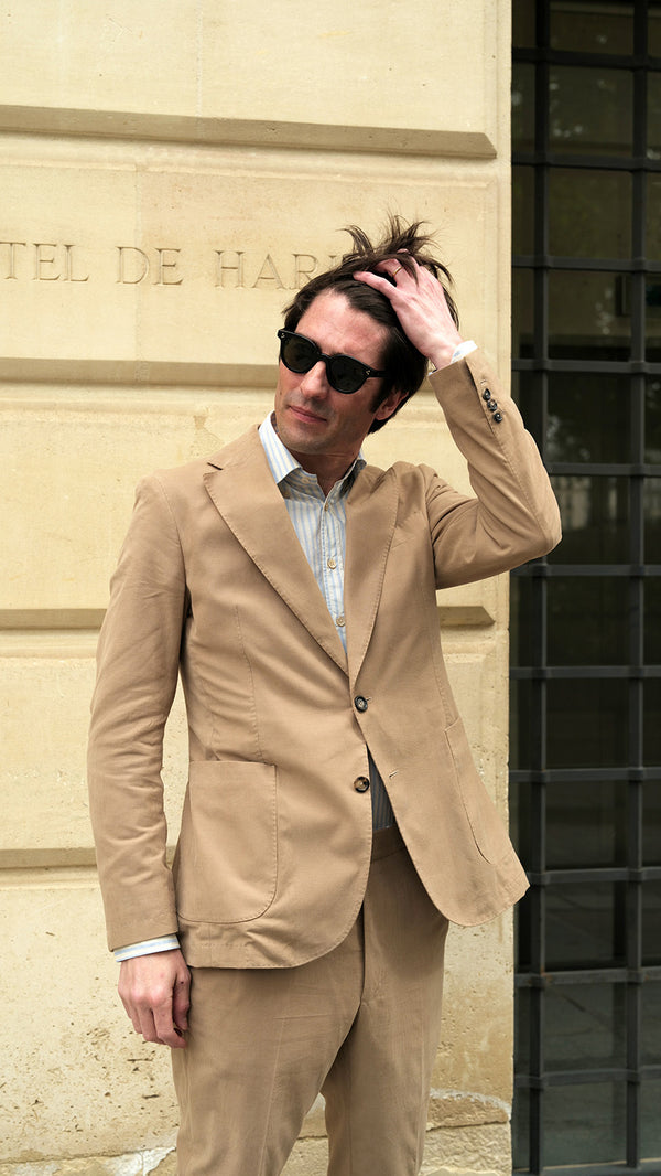 Devant l'Hôtel de Harley, Guillaume porte le costume Charly en milleraies d'été beige de la Maison Gabriel Paris - UNISEXE