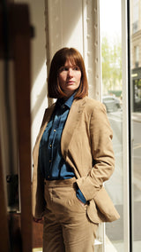 Clémentine pose dans la Galerie Aurélien Serre et porte le costume Charly en milleraies d'été beige de la Maison Gabriel Paris - UNISEXE