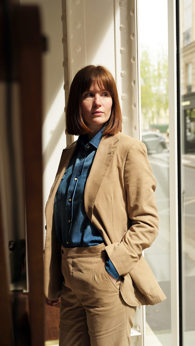 Clémentine pose dans la Galerie Aurélien Serre et porte le costume Charly en milleraies d'été beige de la Maison Gabriel Paris - UNISEXE
