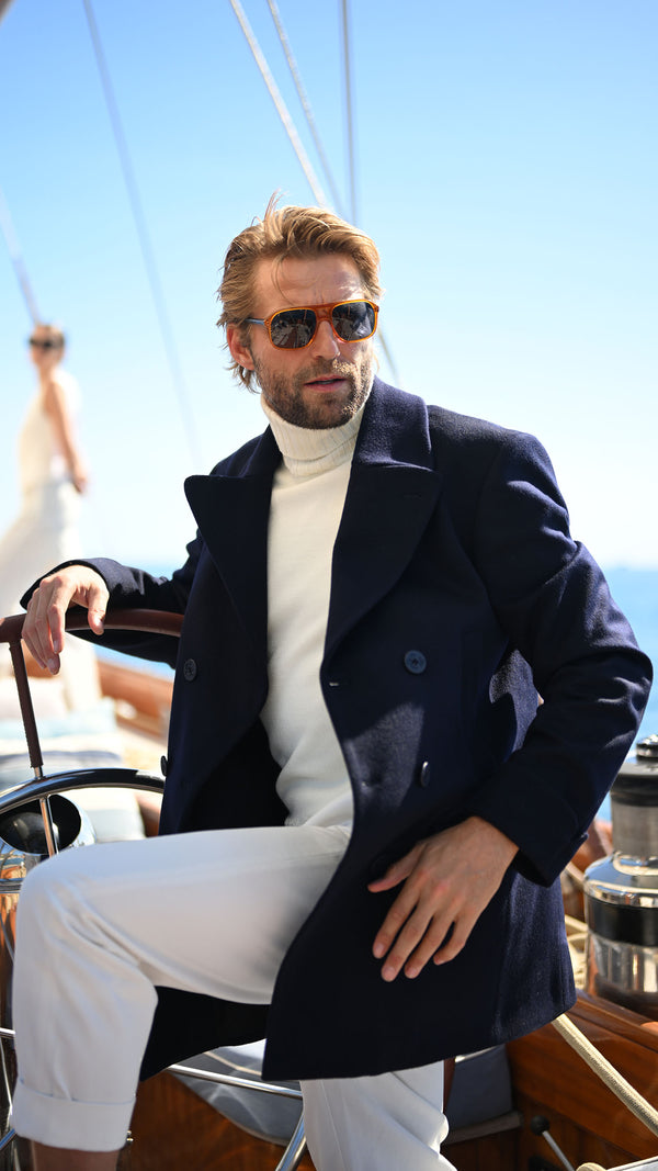 Rein sur le voilier porte le caban Eric couleur navy, le pull Philippe col roulé blanc de la Maison Gabriel Paris