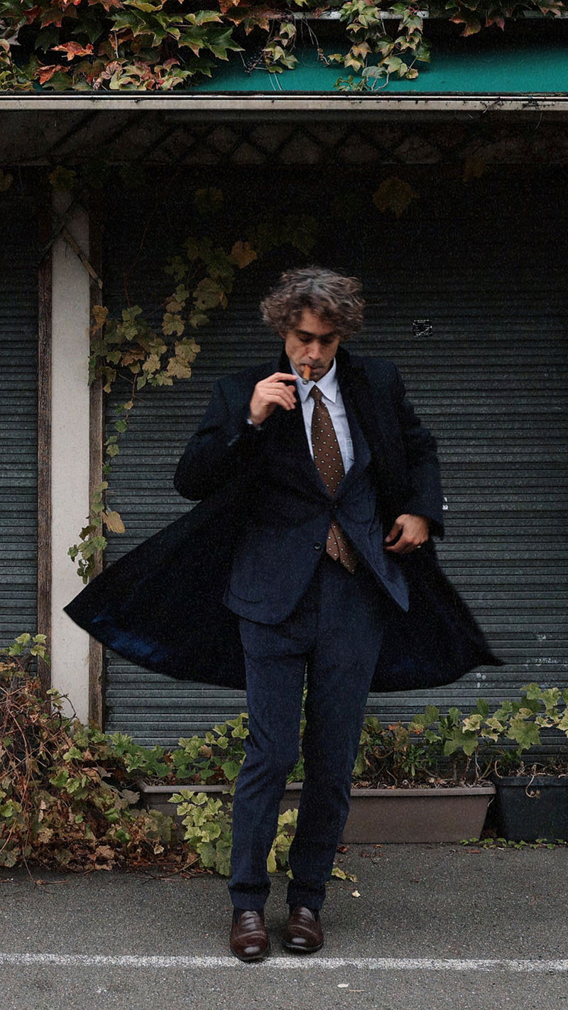 Pablo Saavedra de Decker aux Puces de Saint Ouen porte le manteau droit Hannibal en laine et cachemire bleu marine de la Maison Gabriel Paris