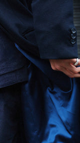 Pablo Saavedra de Decker aux Puces de Saint Ouen porte le manteau droit Hannibal en laine et cachemire bleu marine - détail de la manche - de la Maison Gabriel Paris