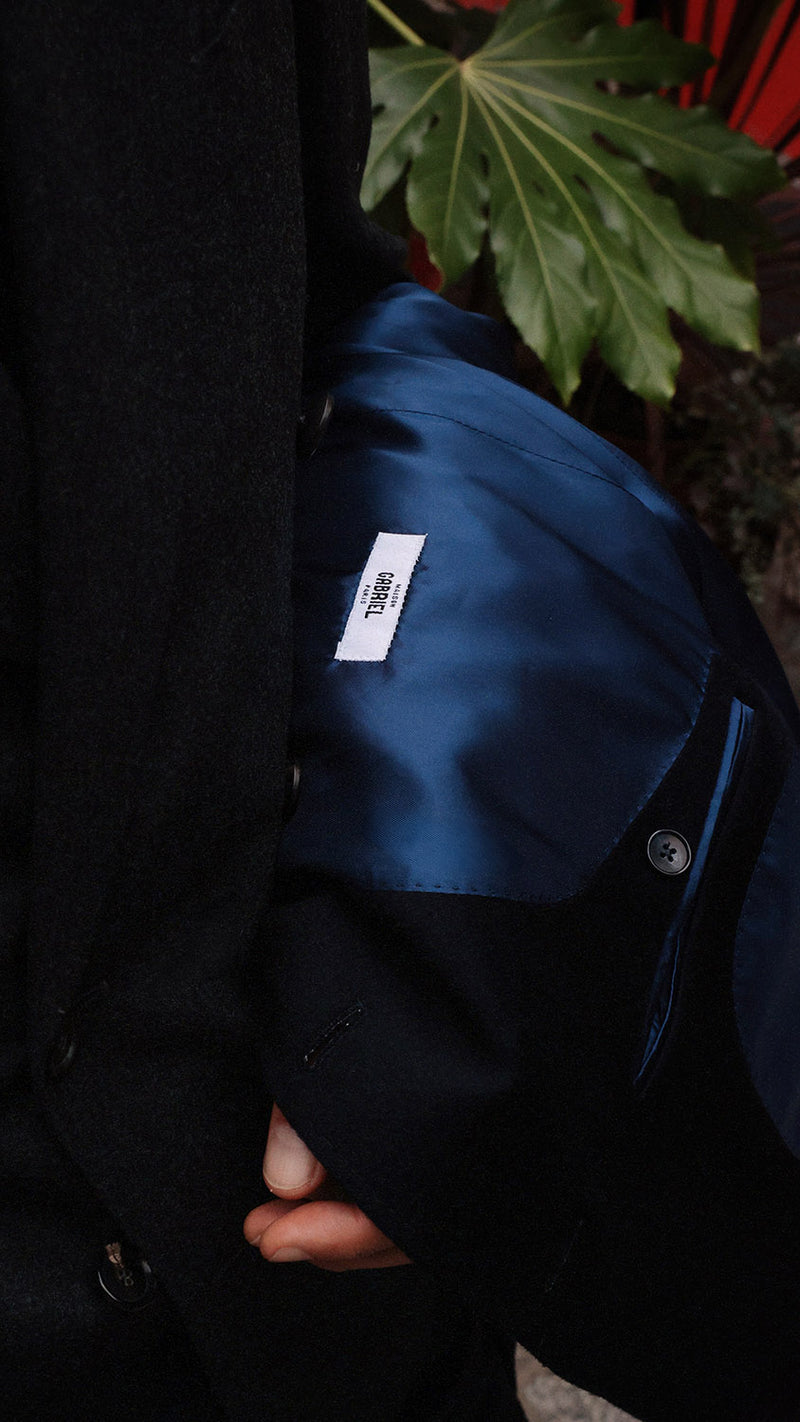 Pablo Saavedra de Decker aux Puces de Saint Ouen porte le manteau droit Hannibal en laine et cachemire bleu marine - détail intérieur - de la Maison Gabriel Paris