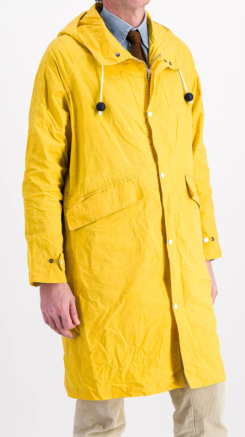 Le mannequin studio porte le manteau de pluie Jean-Louis en wax jaune - 3/4 vue de profil - de la Maison Gabriel Paris