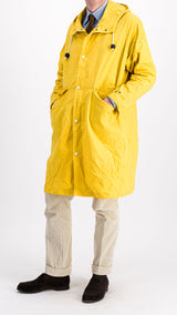 Le mannequin studio porte le manteau de pluie Jean-Louis en wax jaune - vue de face 3/4 - de la Maison Gabriel Paris