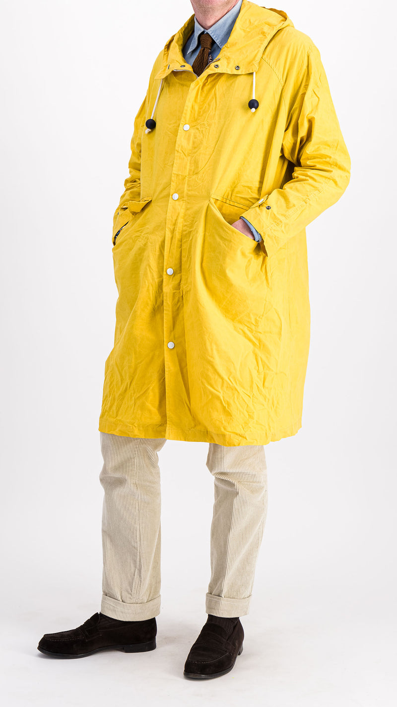 Le mannequin studio porte le manteau de pluie Jean-Louis en wax jaune - vue de face 3/4 - de la Maison Gabriel Paris