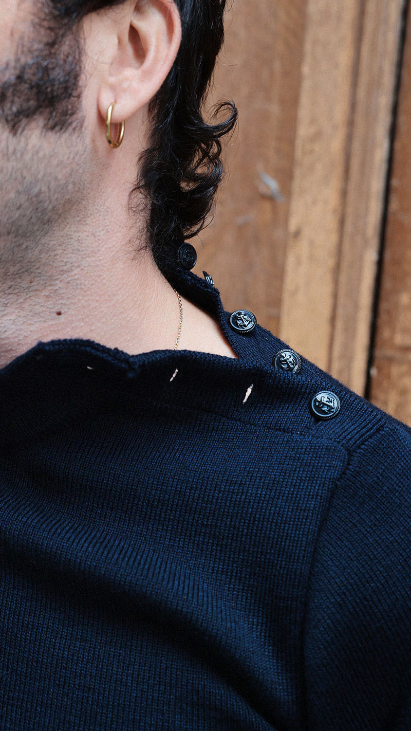 Titouan dans la rue du Mont Thabor porte le pull marin Erwann en laine bleu nuit LE MINOR - Détail boutonnage sur l'épaule - Collection Automne Hiver 2025 - Maison Gabriel Paris