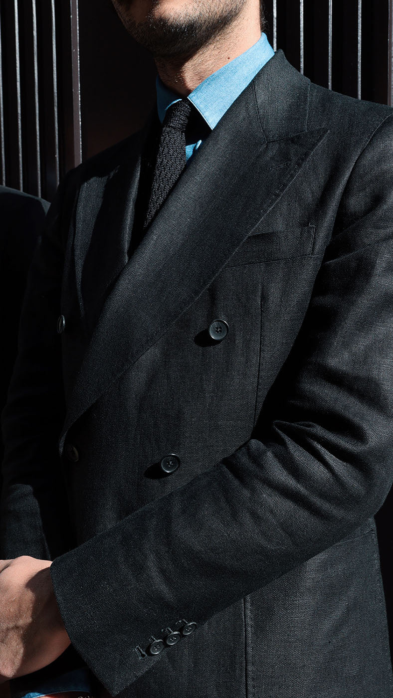 Détail de la veste du costume croisé Titouan en lin irlandais noir porté par Titouan devant l'Hôtel Coste à Paris  - Collection Printemps Été 2025 par Maison Gabriel Paris