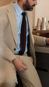 Élie porte le costume droit Raphel en lin et coton coloris mastic - photographié au bar du restaurant parisien Alfi's - Collection Printemps-Été 2025 - Maison Gabriel Paris
