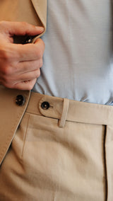 Élie porte le costume droit Raphel en lin et coton coloris mastic - détail de la ceinture du pantalon photographié dans le restaurant parisien Alfi's - Collection Printemps-Été 2025 - Maison Gabriel Paris