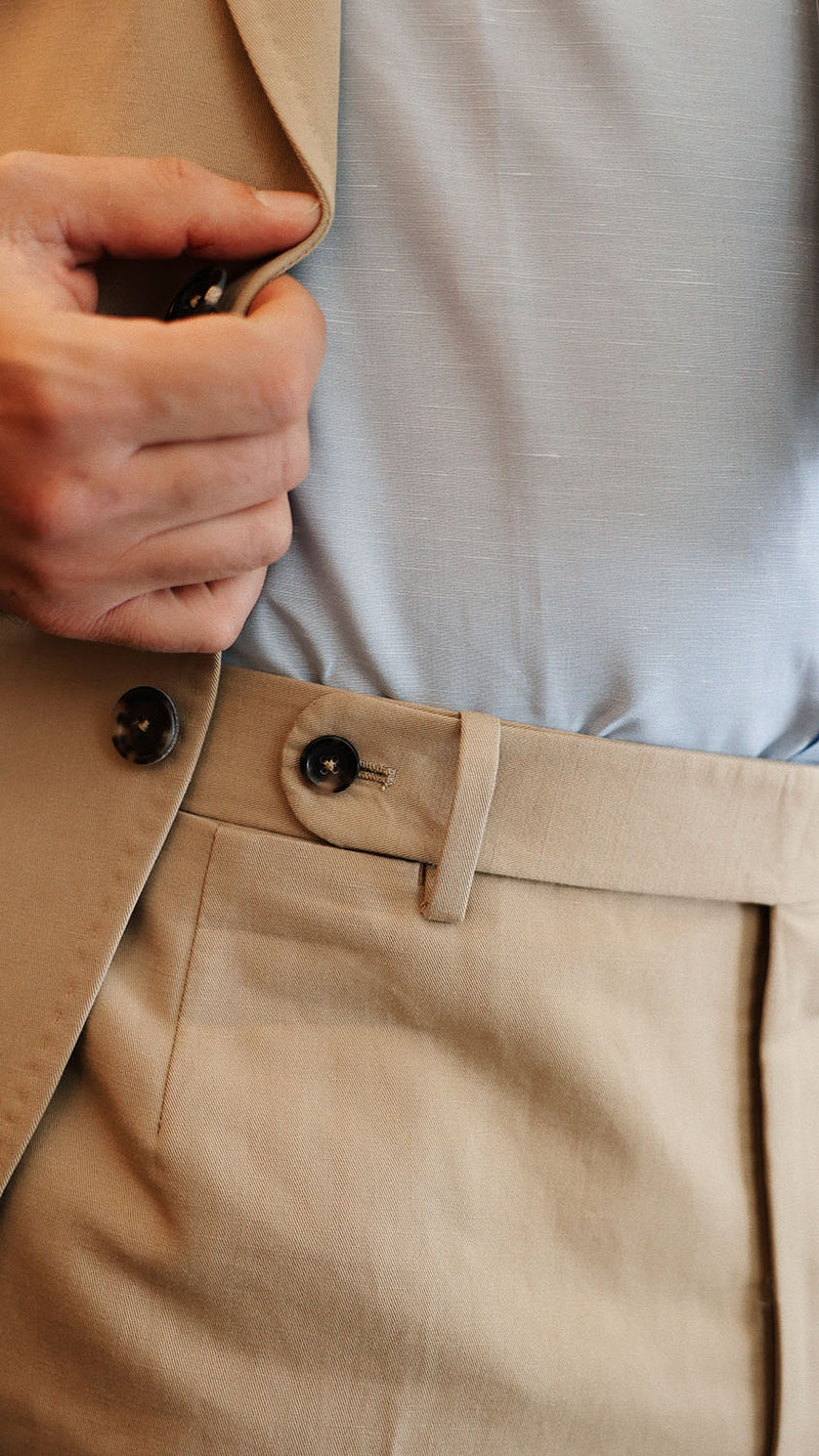 Élie porte le costume droit Raphel en lin et coton coloris mastic - détail de la ceinture du pantalon photographié dans le restaurant parisien Alfi's - Collection Printemps-Été 2025 - Maison Gabriel Paris